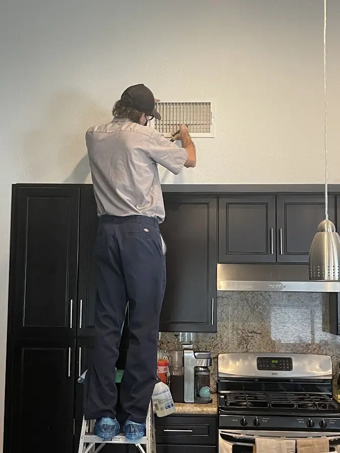 Technician inspecting an air vent during HVAC service in Dent